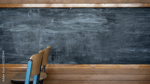 Empty blackboard in a classroom in school with wooden chairs and table