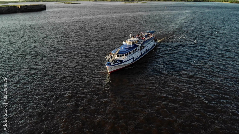 Obraz premium Cruise ship sailing across river - aerial footage. A lot of seagulls near the liner