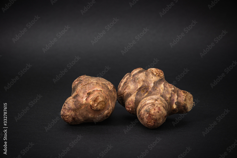 Jerusalem artichoke on a dark background. The concept of eating and using unusual plants for food.