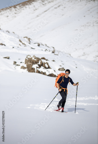 Winter sports - young man walking with snowshoes in high mountains covered with lots of snow (selective focus on the mountain in the background)