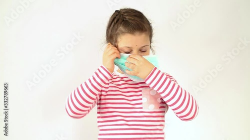 A little Caucasian girl is demonstrating how to properly wear a mask against coronavirus covid-19 and protection against biological weapons of pollution.Coronavirus Protection Concept, COVID-19. Pande photo