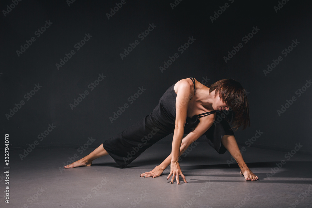Portrait of a beautiful woman dancing on black background. Ballet and contemporary dancer dancing on dark backdrop. Contemporary Art. Plastic and flexible girl in black clothes posing on a black wall Portrait of a beautiful woman dancing on black background. Ballet and contemporary dancer dancing on dark backdrop. Contemporary Art. Plastic and flexible girl in black clothes posing on a black wall