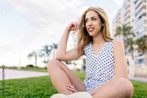Blue-eyed girl in a hat rests on the grass on a summer afternoon during her vacation