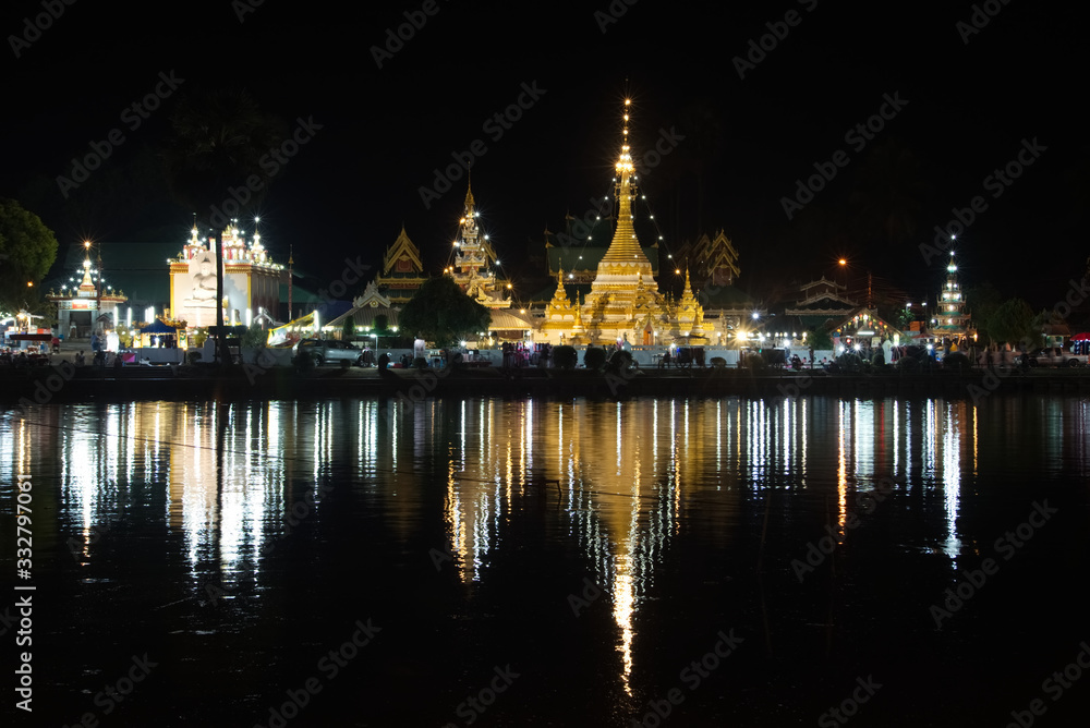 Buddhist pagoda night light with light trail reflection on lake surface, Thailand