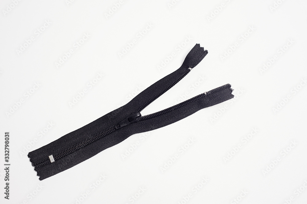 Black half- unbuttoned zipper for clothing. Close- up isolated on a white background. Black half- unbuttoned zipper for clothing. Close- up isolated on a white background.