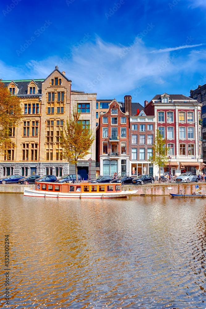 Traditional Dutch Cityscape Of Amsterdam With Barge in the Foreground At Daytime.