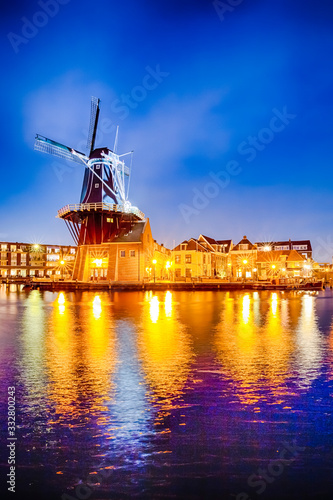 Travel Destinations. Night View of Harlem Sight With De Adriaan Windmill on Spaarne River On The Background During Blue Hour.
