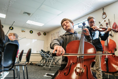 Teenage girl and boy playing cello and violin in classroom