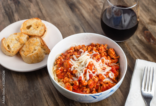 Pasta with meat sauce and mozzarella, garlic bread and red wine