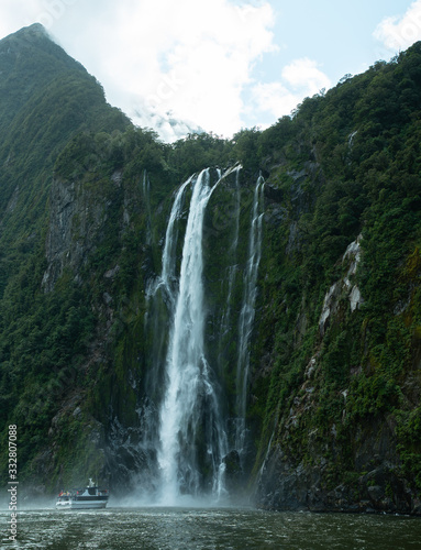 Boat goes into waterfall at a fjord in Milford Sound New Zealand