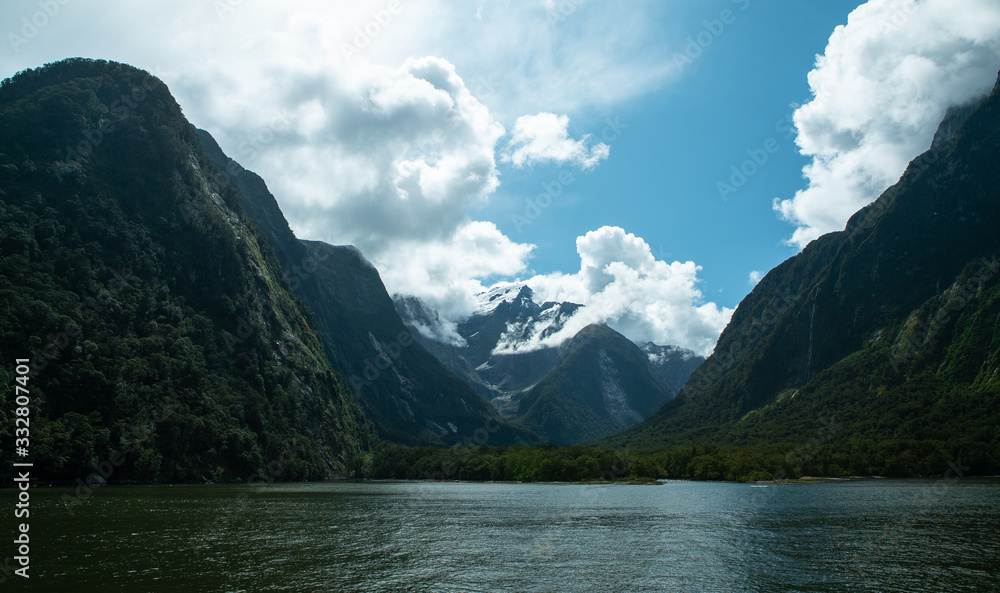 Rolling clouds come over a mountain at the fjord Milford Sound in New Zealand