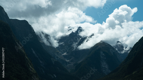 Rolling clouds come over a mountain at the fjord Milford Sound in New Zealand