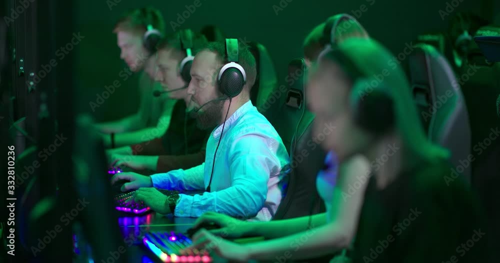 Group of hotline workers sit at workplaces in headphones with microphones and talk with customers. Hotline staff are sitting in a row, a dark call center night shift hall. Group of hotline workers sit at workplaces in headphones with microphones and talk with customers. Hotline staff are sitting in a row, a dark call center night shift hall.