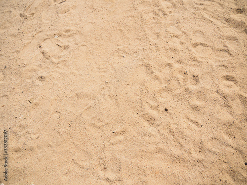 Sandy beach, top view. Texture of sand with track of legs. Close up photo of sand on tropical beach. Background for travel and vacation