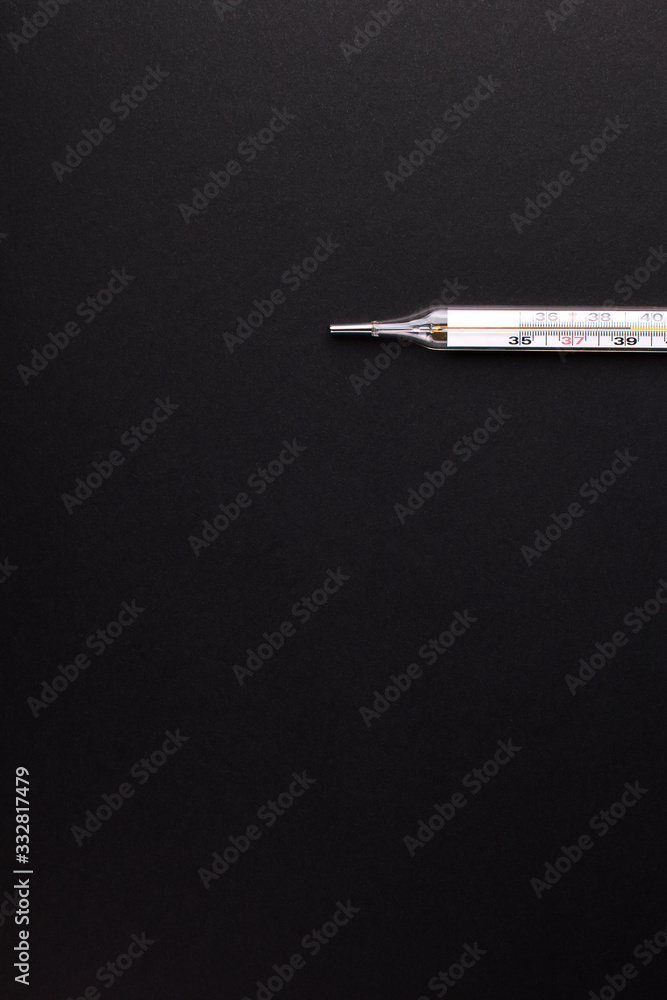 Medical thermometer with a temperature of 39 on a black paper background, copy space, vertical orientation. Medical thermometer with a temperature of 39 on a black paper background, copy space, vertical orientation.