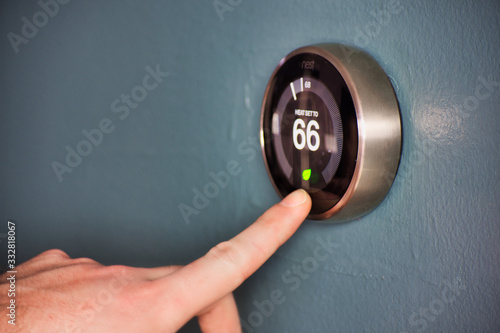 Foto Hand operating smart thermostat to save money