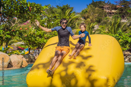 Dad and son go through an inflatable obstacle course in the pool © galitskaya