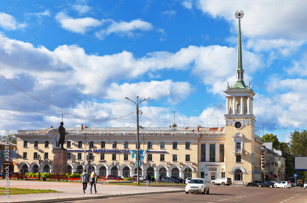 Siberian city of Angarsk. Spire of a tower with a city clock in the city center against a blue sky with clouds. Beautiful cityscape of the historic city center