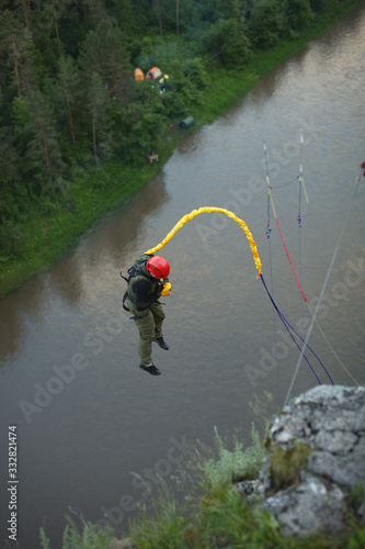 Athlete falls down against the background of a river tied to a safety rope. Ropejumping.