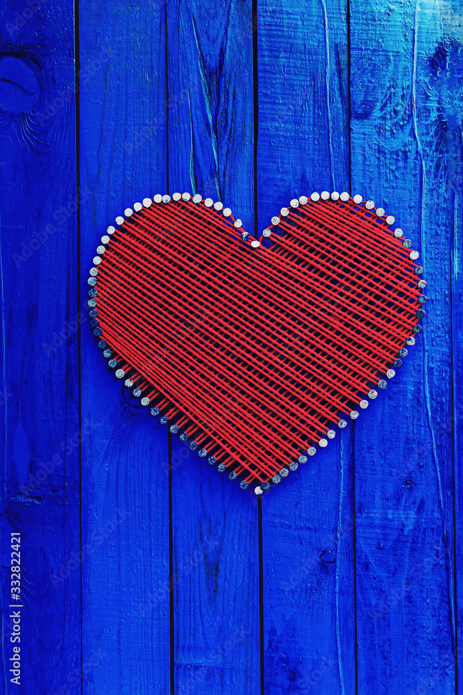 Antique blue wood sign with red and white hearts on burlap background hanging by braided rope on aged wooden fence Antique blue wood sign with red and white hearts on burlap background hanging by braided rope on aged wooden fence