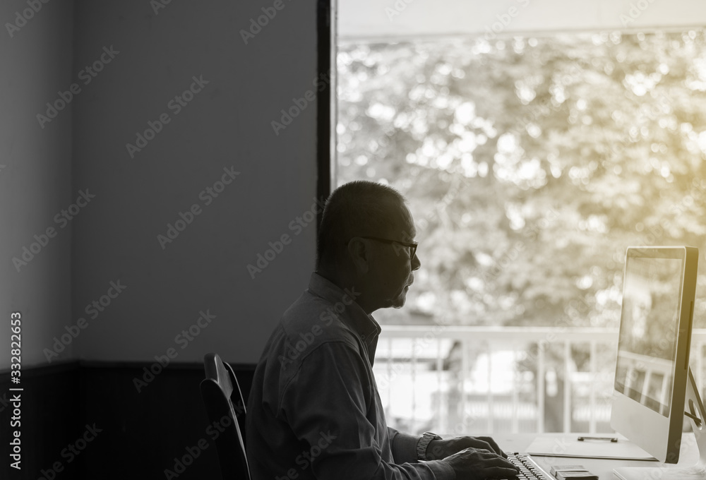 Asian senior businessman using a laptop computer at home,Black and white toned. Asian senior businessman using a laptop computer at home,Black and white toned.