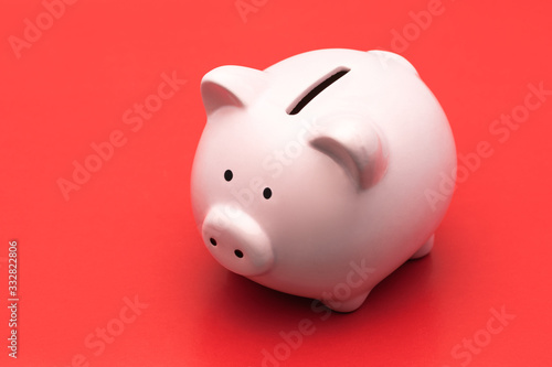 A pink piggy Bank stands on a bright red background with a shadow. Horizontal photography