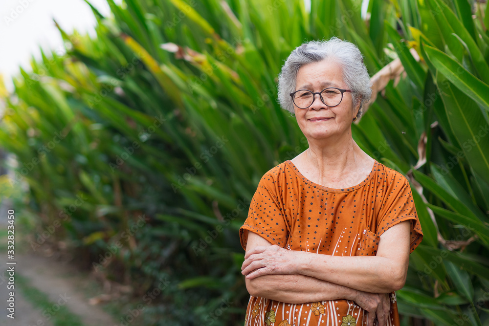 Portrait of elderly woman with short white hair standing smile and looking at the camera in garden. Asian old woman healthy and have positive thoughts on life make her happy every day. Health concept Portrait of elderly woman with short white hair standing smile and looking at the camera in garden. Asian old woman healthy and have positive thoughts on life make her happy every day. Health concept