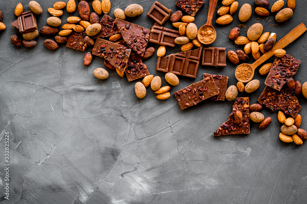 Sweets frame. Broken chocolate slices and nuts on grey stone background top-down copy space