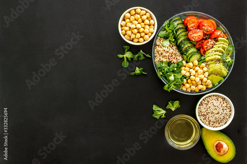 Vegan Buddha bowl. Avocado, quinoa, tomato, spinach and chickpeas vegetables salad on black table top-down copy space