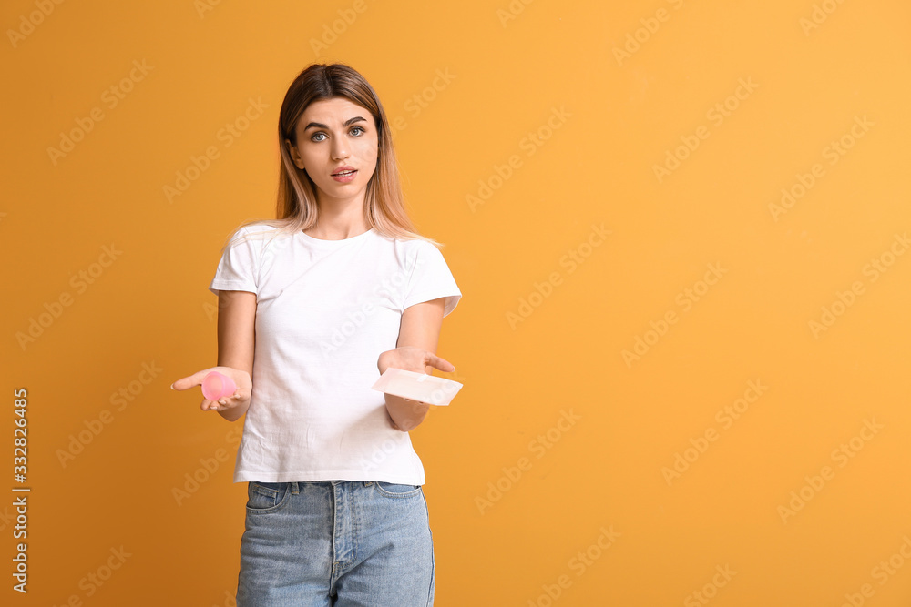 Young woman with menstrual pad and cup on color background Young woman with menstrual pad and cup on color background