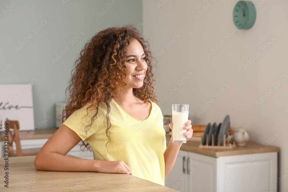 Young African-American woman with milk in kitchen Young African-American woman with milk in kitchen