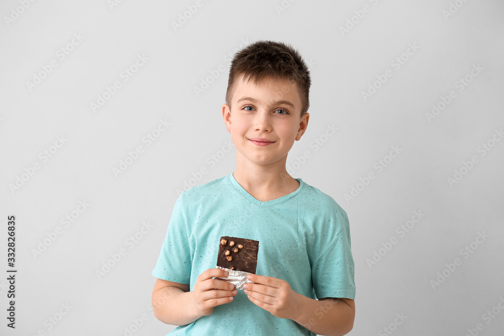 Cute little boy eating chocolate on light background Cute little boy eating chocolate on light background