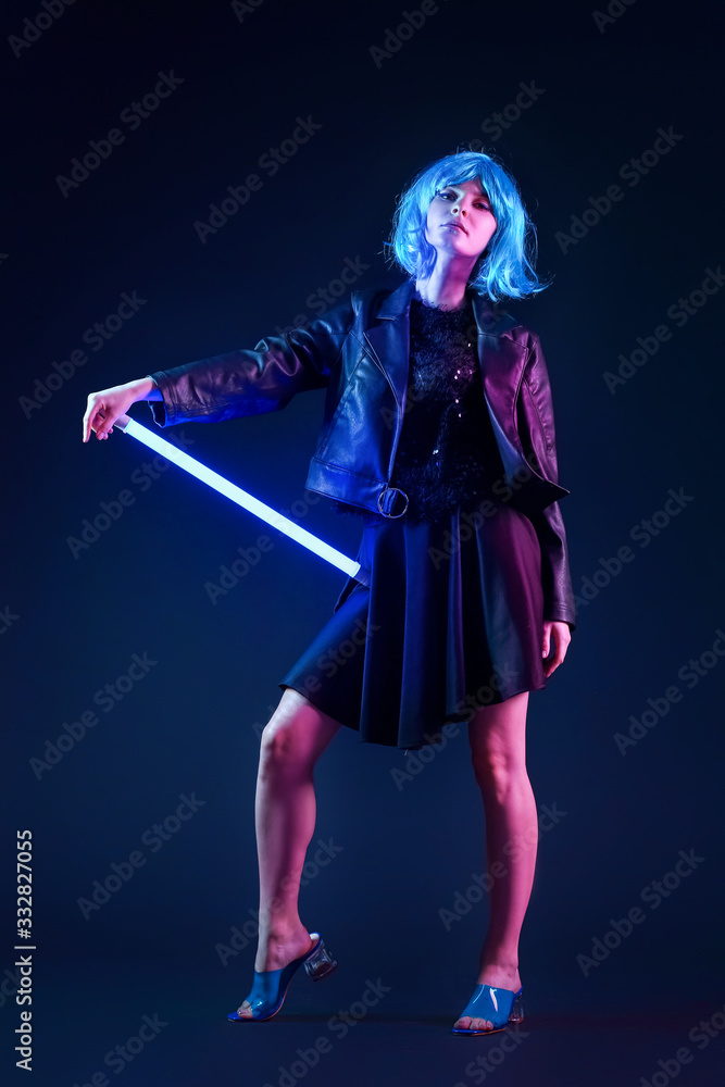 Toned portrait of beautiful woman with neon lamp on dark background