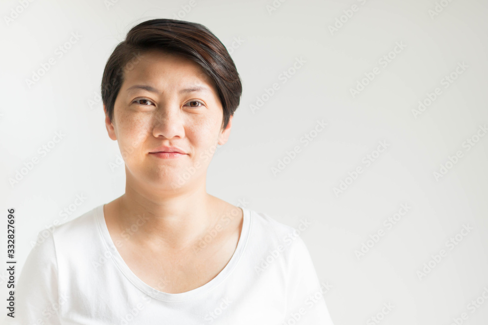 A portrait of Asian 40s short hair woman with freckles, wrinkles, and furrow on the face; smiling and looking forward on white background. A portrait of Asian 40s short hair woman with freckles, wrinkles, and furrow on the face; smiling and looking forward on white background.
