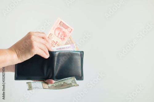 Hands picking Rupees money from the short wallet for payment in the Republic of India.