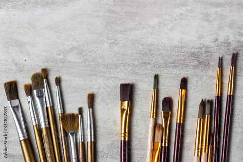Paint brushes scattered across the table on a gray background, drawing tools top view, copy space, close-up