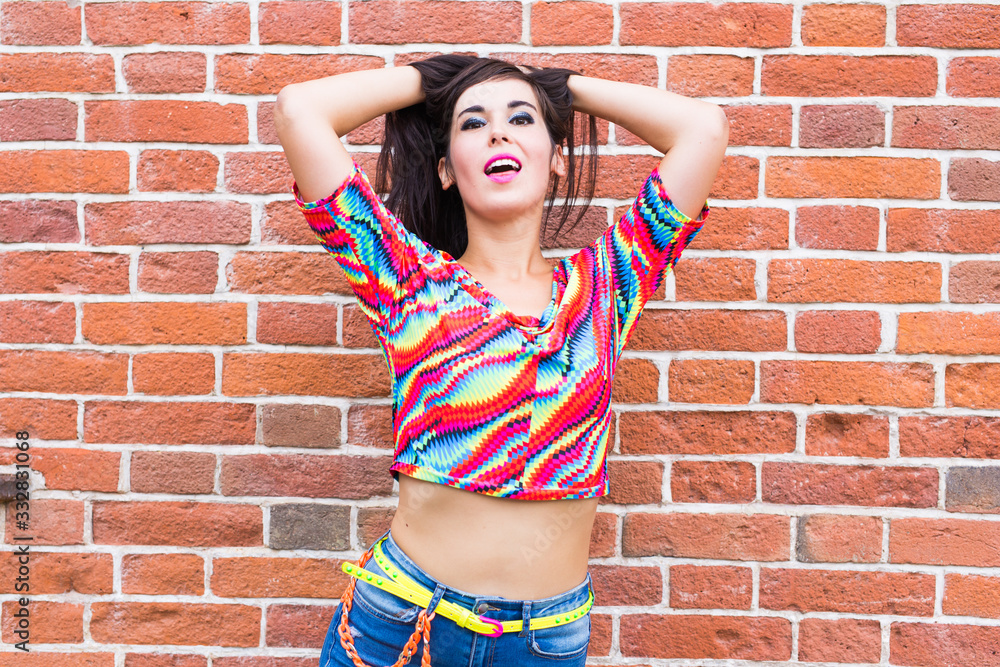 Fashion and urban style concept - Portrait of a beautiful woman in blue jeans against a white brick wall. Fashion and urban style concept - Portrait of a beautiful woman in blue jeans against a white brick wall.