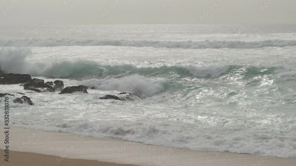 Big, powerful waves splashing on rocks in slow motion and throwing spray into the air. Foggy day at the atlantic coast in Portugal. Big, powerful waves splashing on rocks in slow motion and throwing spray into the air. Foggy day at the atlantic coast in Portugal.