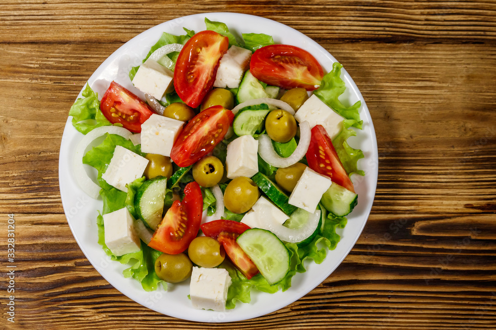 Greek salad with fresh vegetables, feta cheese and green olives on wooden table. Top view