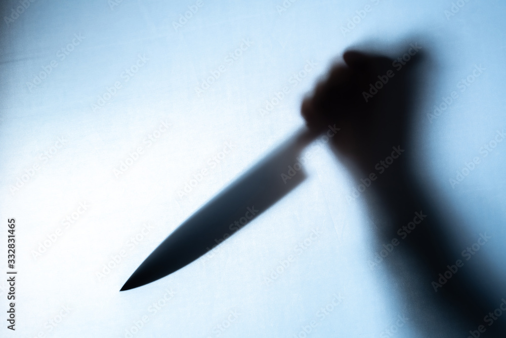 Blurred shadow of a hand holding a big and sharp knife Blurred shadow of a hand holding a big and sharp knife