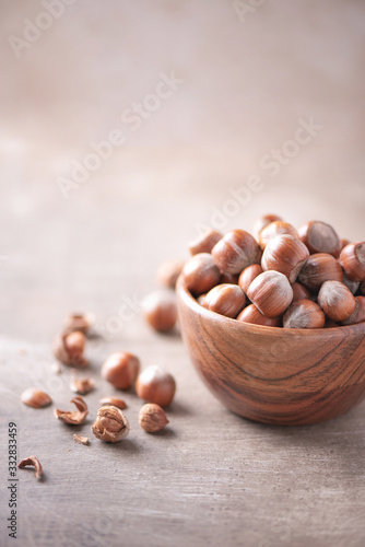 Hazelnuts in wooden bowl on wood textured background. Copy space. Superfood, vegan, vegetarian food concept. Macro of hazelnut, selective focus. Healthy snack.