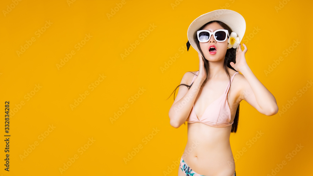 Beautiful,Sexy asian girl standing on yellow background in a colors bikini and smiling.Summer vocation happy trip concept. Beautiful,Sexy asian girl standing on yellow background in a colors bikini and smiling.Summer vocation happy trip concept.