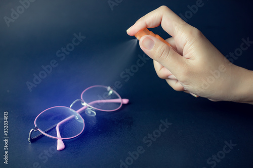 Cleaning the eyeglasses using alcohol spray  for hygiene protect weak ill chemotherapy for safety,infection of Covid-19 virus,coronavirus - 2019-nCoV, Covid-19, WUHAN virus concept. photo