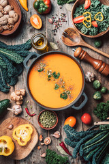 Vegan diet. Autumn harvest. Healthy, clean food and eating concept. Zero waste. Pumpkin soup with vegetarian cooking ingredients, wooden spoons, kitchen utensils on wooden background. Top view