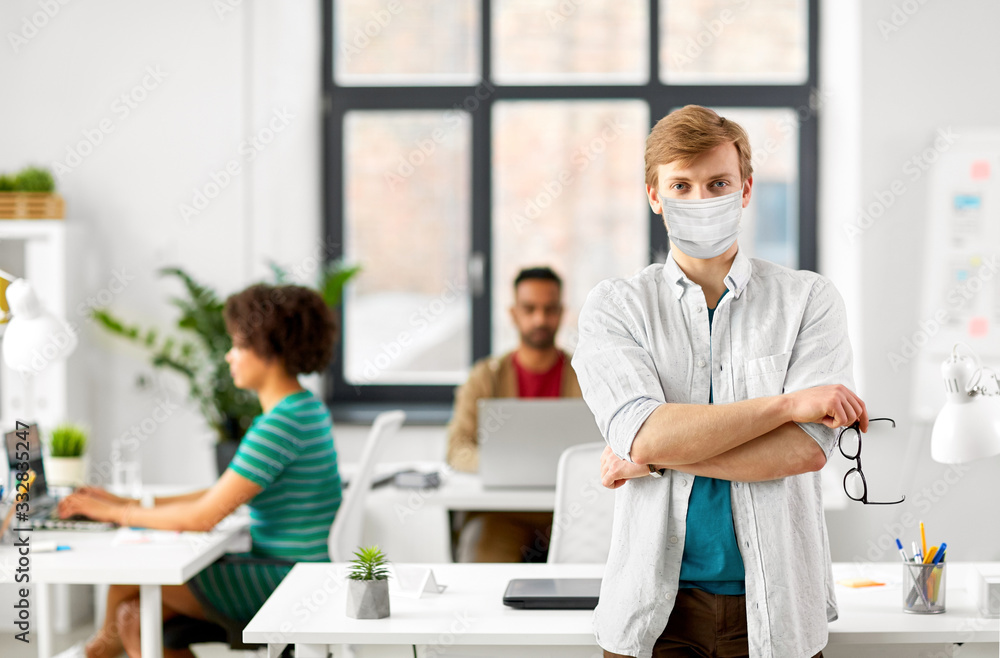 Obraz premium business and people concept - man with glasses wearing protective medical mask for protection from virus disease at office