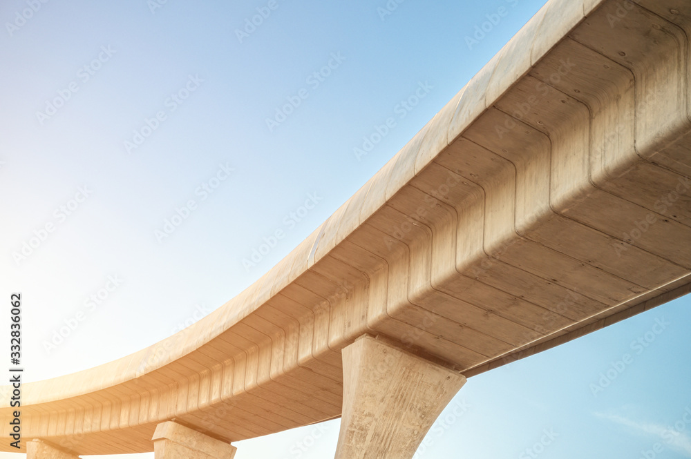 Fototapeta premium Looking up skytrain viaduct in downtown with blue clear sky. A mass transit train line in progress.