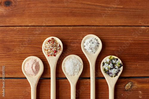 food, culinary and unhealthy eating concept - spoons with salt and spices on wooden table