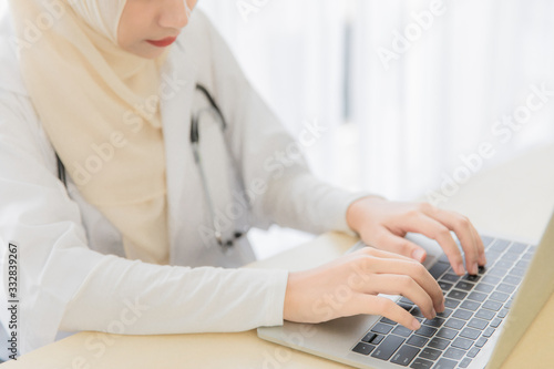 Female muslim doctor typing on keyboard