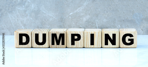 DUMPING , the word on the cubes on a gray marble background. Business concept © Zhanna