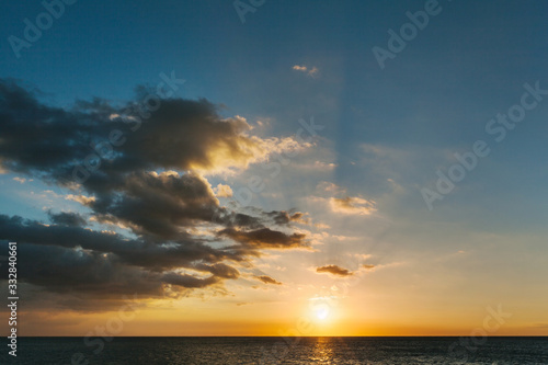 Dramatic golden sunset over Pacific ocean with rays of sun beams and blue sky